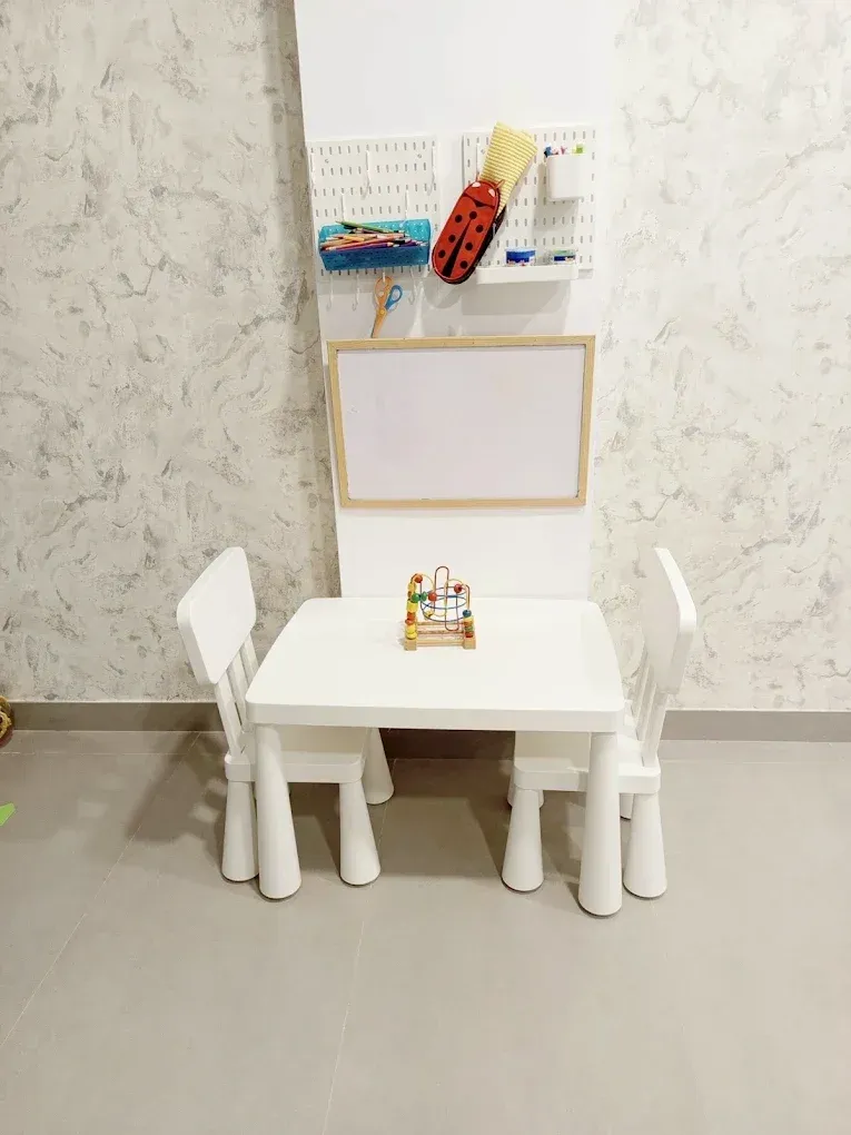 Rincón infantil con mesa baja, sillas pequeñas y pizarra.