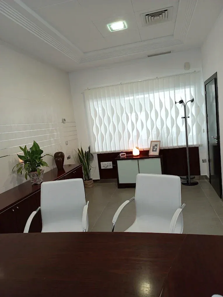 El despacho de consulta desde detrás de la mesa, con la ventana y la luz natural al fondo.