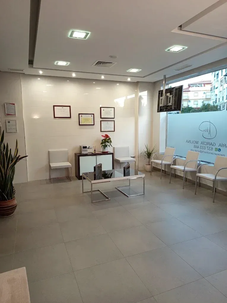 Sala de espera con asientos y las titulaciones enmarcadas.